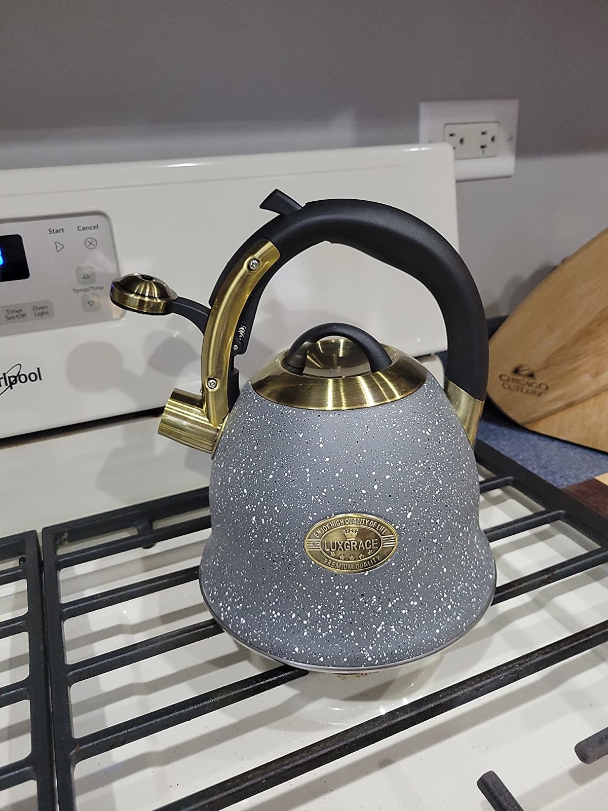 Gray and white speckled tea kettle with gold accents on stovetop