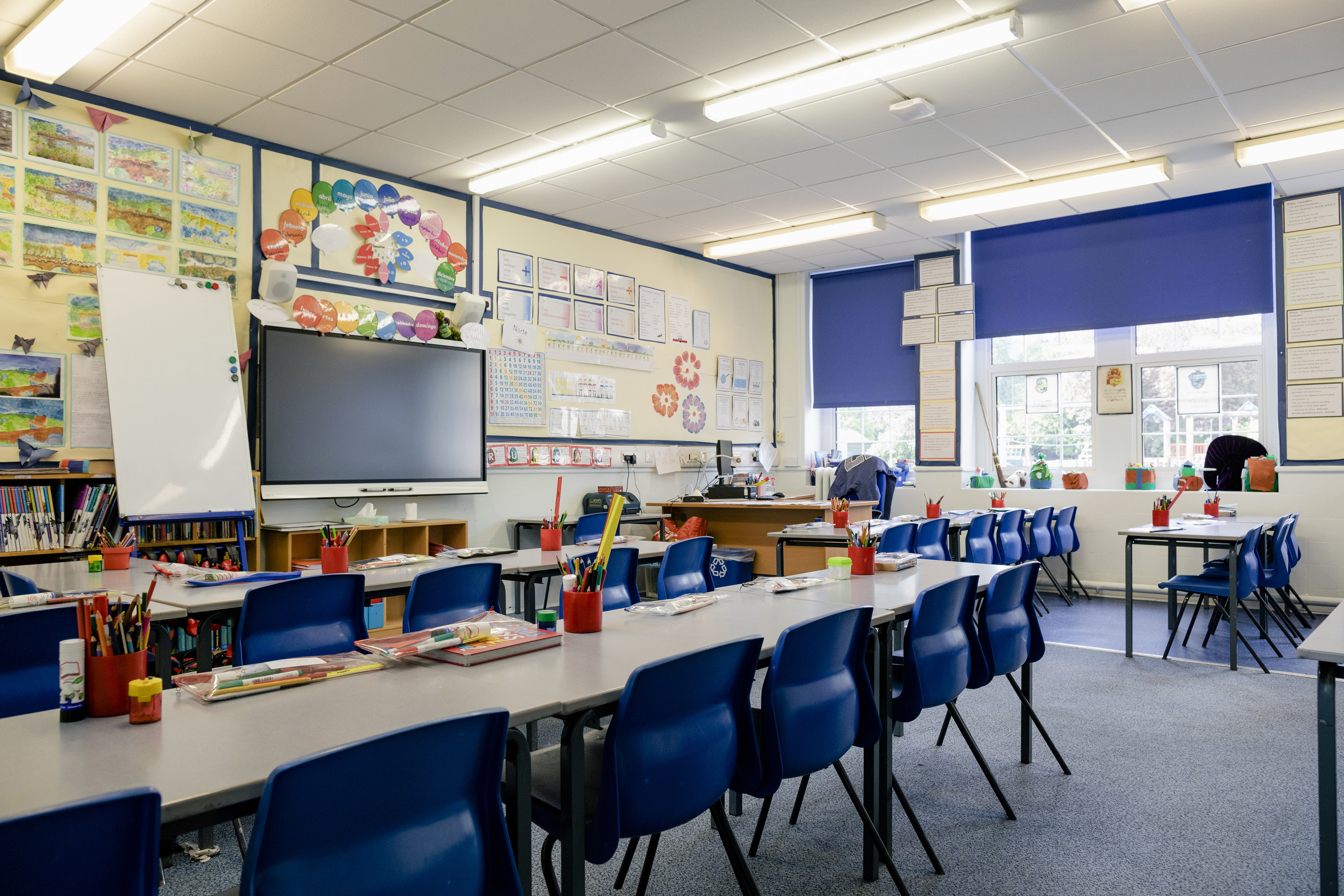 An empty classroom showing long tables with blue chairs