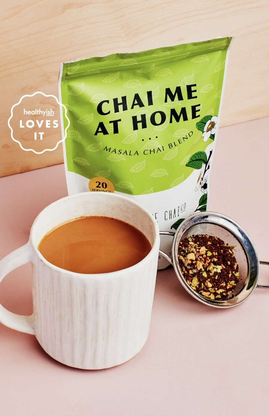 A mug with the masala chai tea sitting next to the bag and loose leaf tea blend