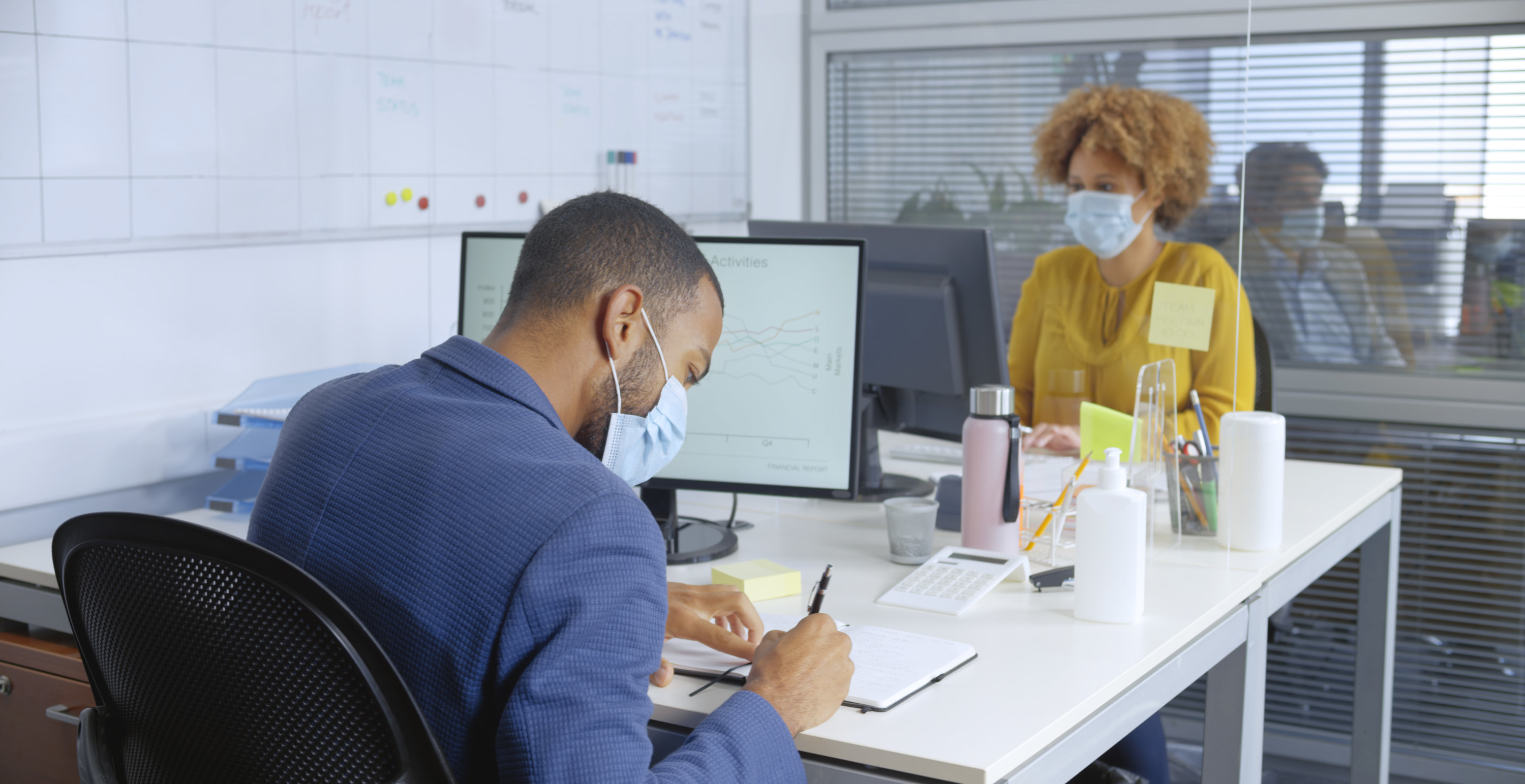 A man and a woman working at a desk in front of their computers