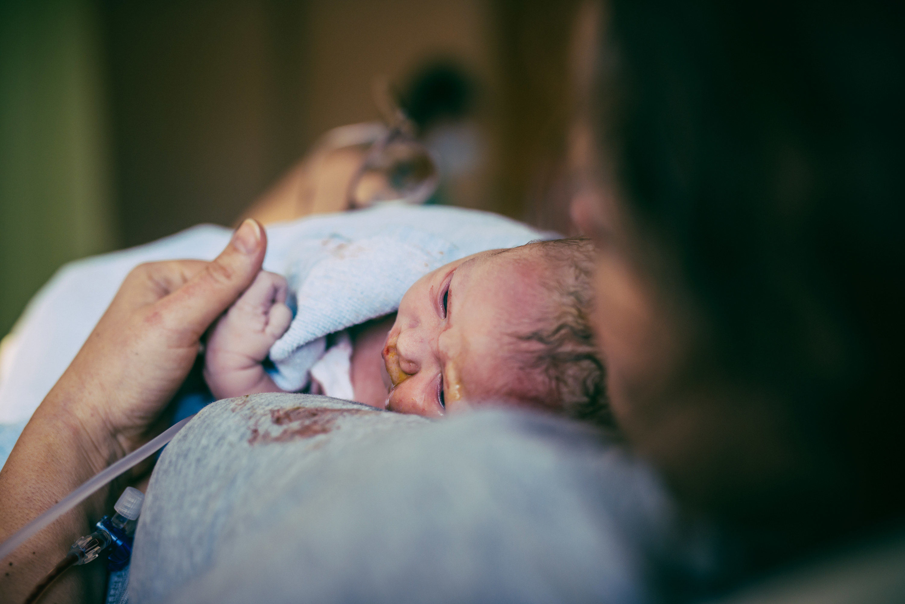 A newborn baby laying on a woman&#x27;s chest