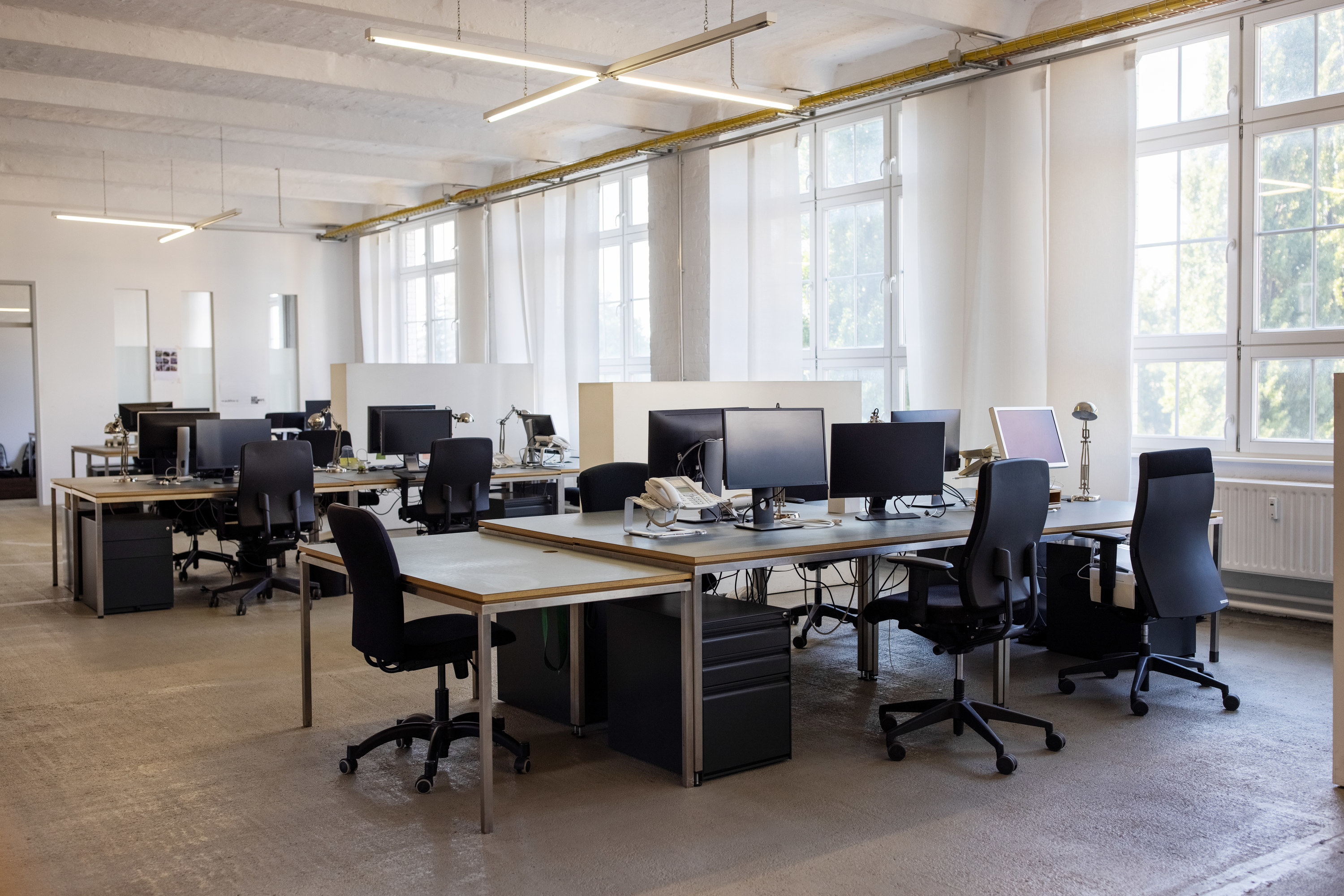 An empty office with multiple black chairs and monitor screens