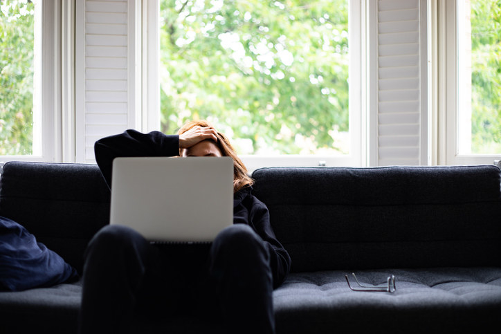 A woman sitting on a sofa, feeling depressed, looking for a job.