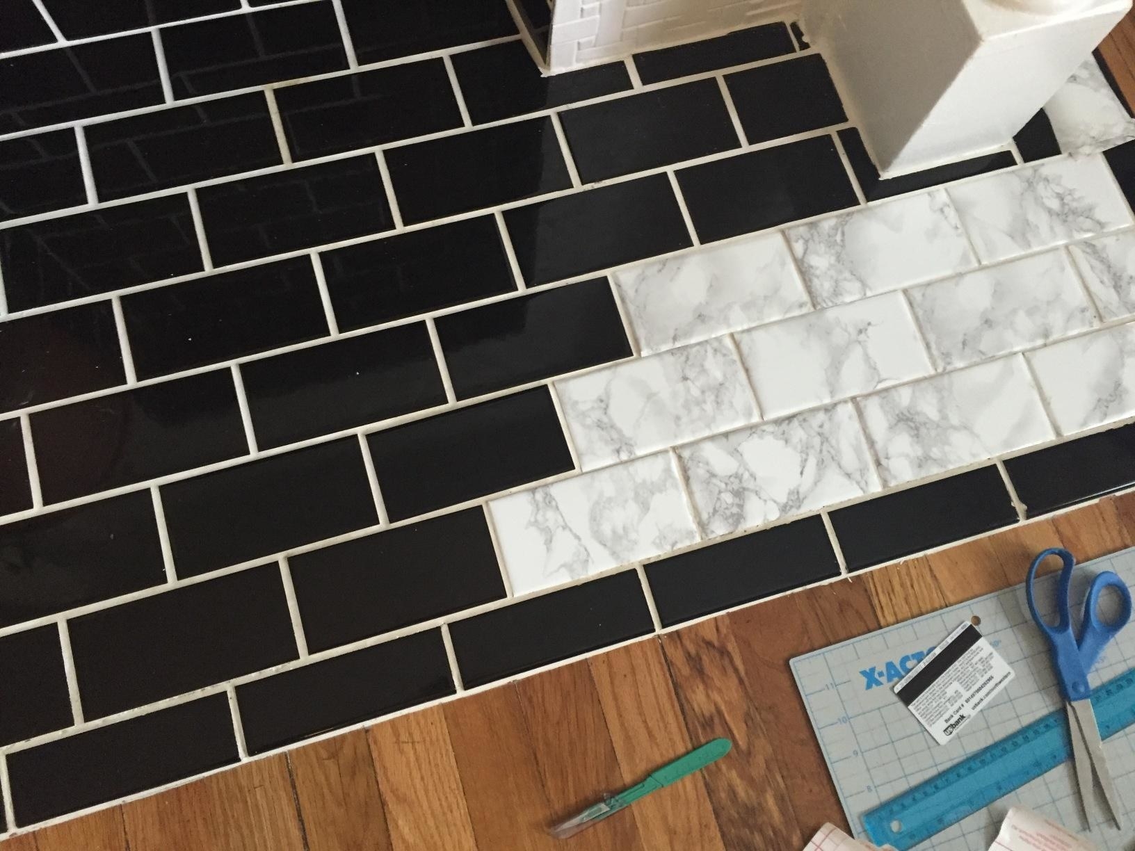review photo of black tiles being covered in fake marble