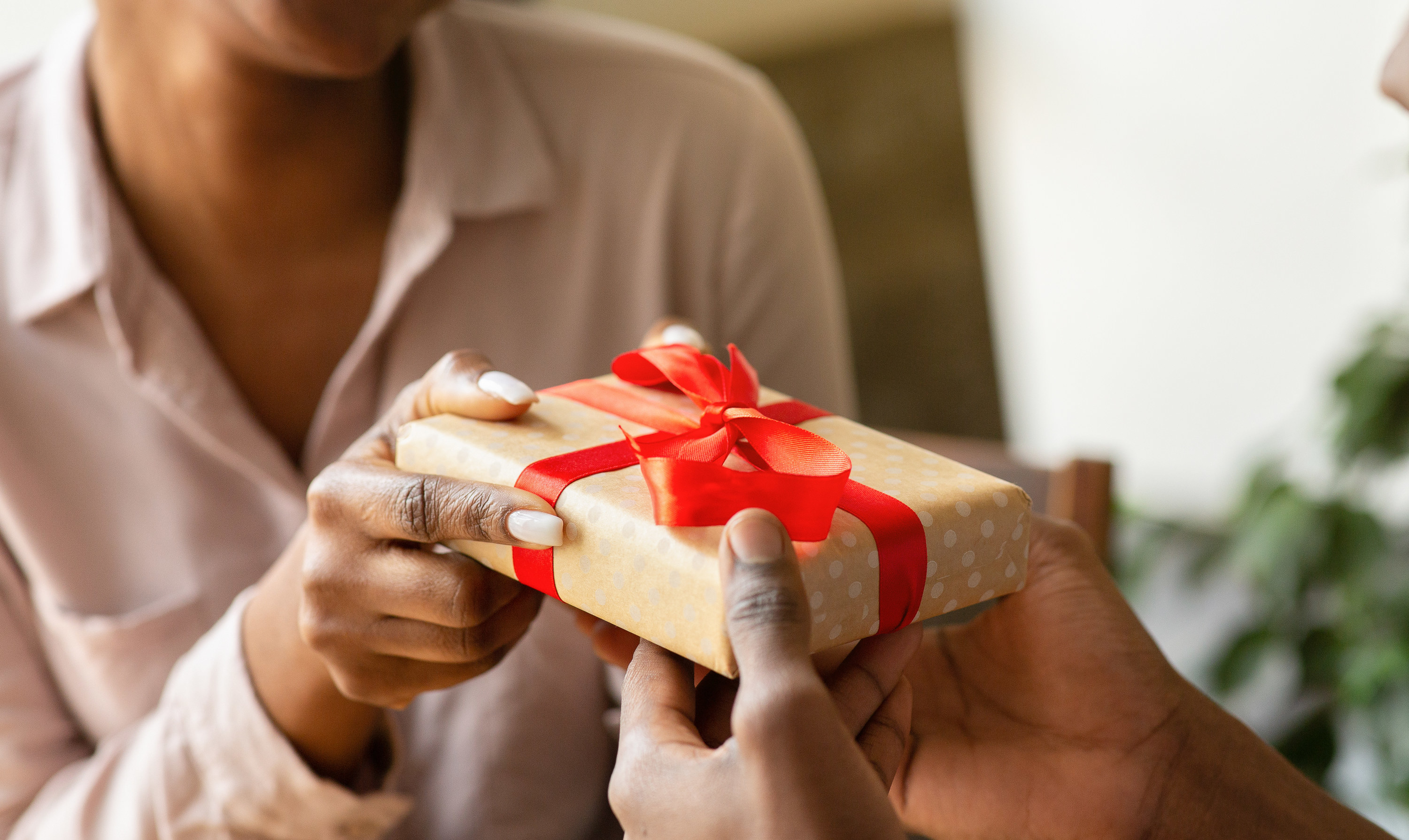 A woman giving a present to a person in their home