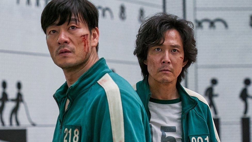 sang-woo and gi-hun looking battered in the squid game sleeping quarters