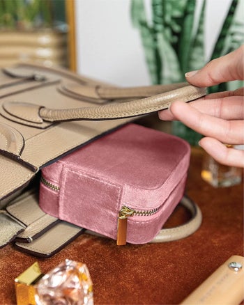 Model sliding pink product into cream purse