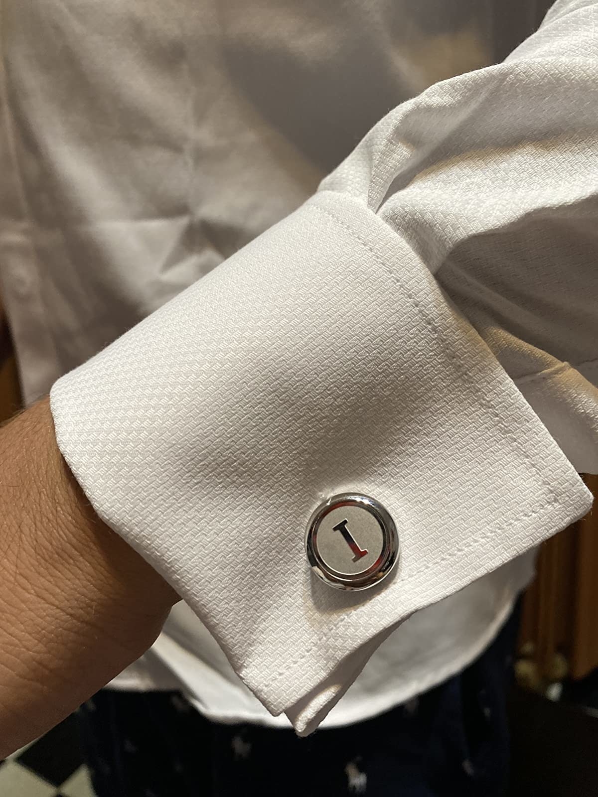 A reviewer&#x27;s round silver tone cufflink with an I