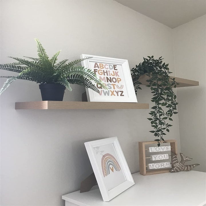 reviewer photo showing two light wood shelves used for plants and photos