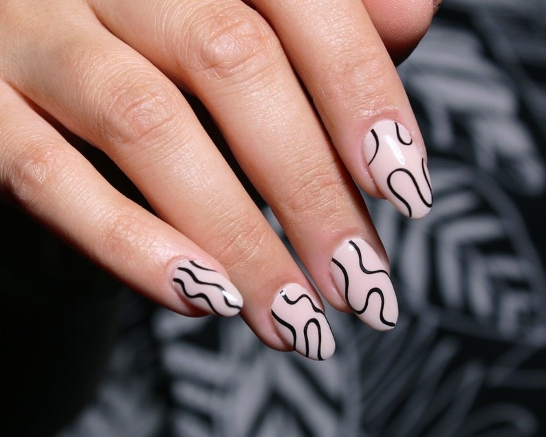 pale pink nail wraps with black squiggly abstract lines on them