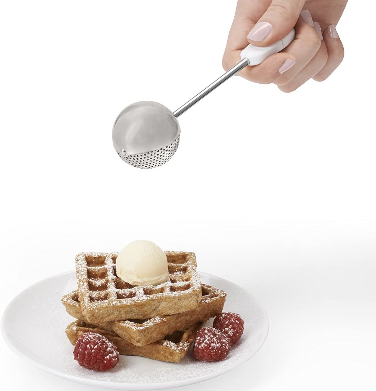 Model&#x27;s hand using the dusting wand to sprinkle powdered sugar on a stack of waffles