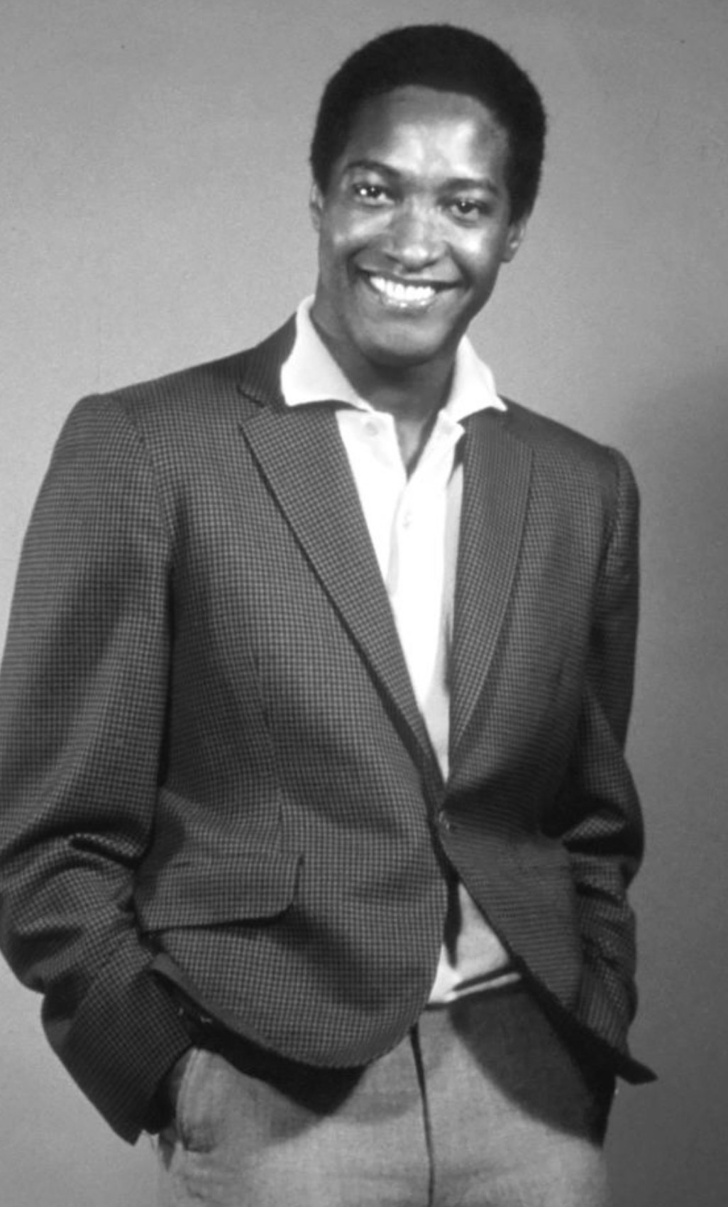Cooke smiling while wearing a fancy blazer with an unbuttoned dress shirt underneath, early &#x27;60s