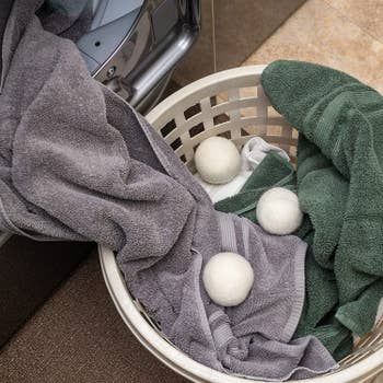 three of the baseball-sized dryer balls in a laundry basket with towels