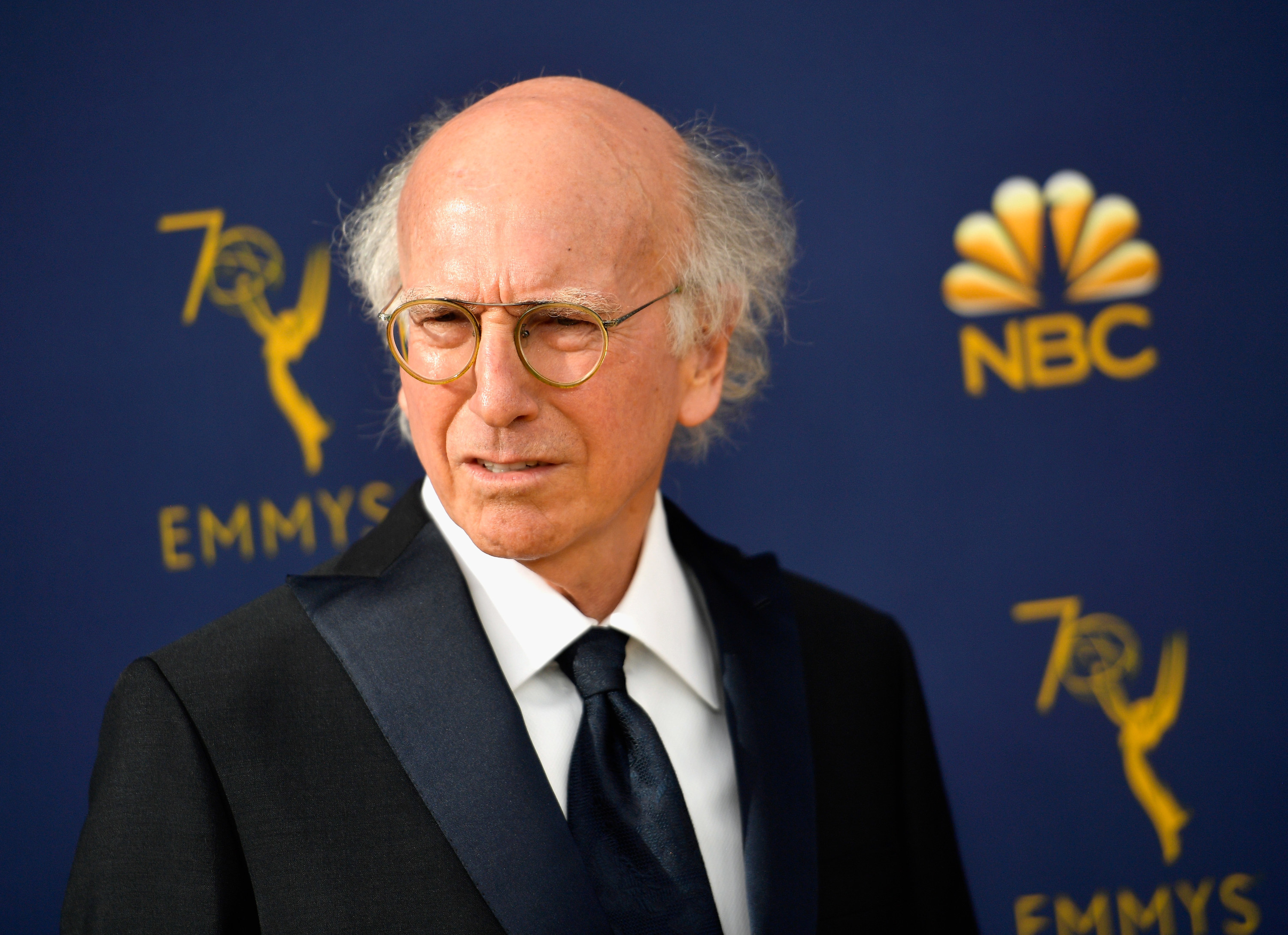 larry david giving a confused look with his signature grey hair parted in the middle