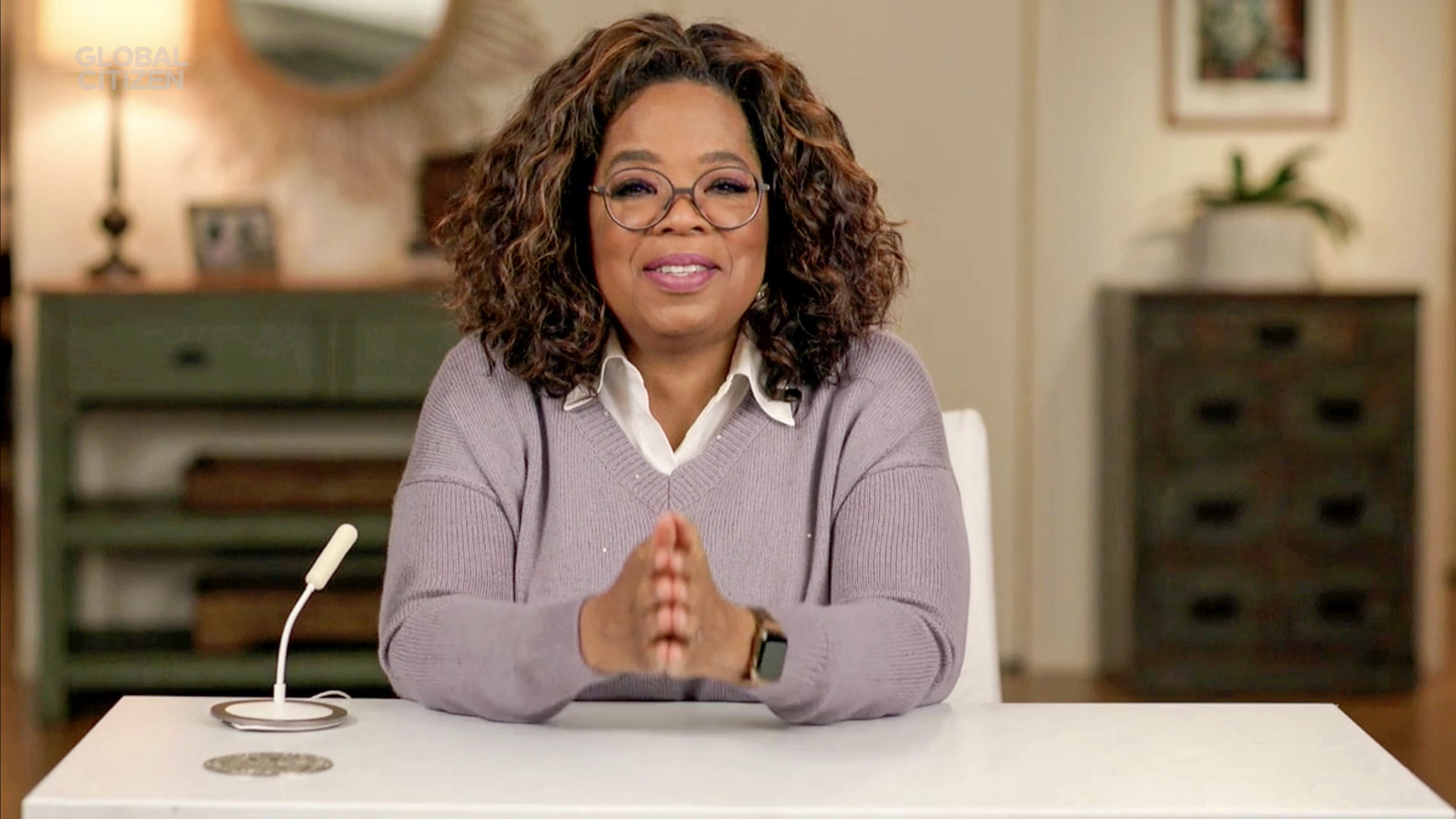 Oprah at a desk with her hands clasped together