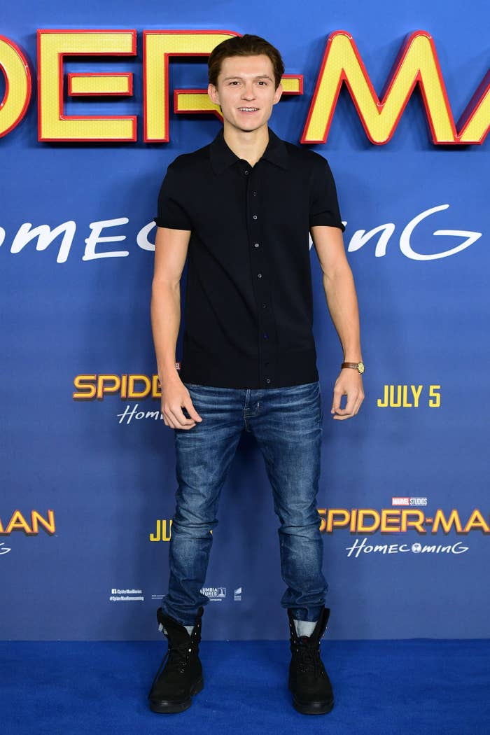 Tom wearing a polo, jeans tucked into boots, and his hair slicked back on the red carpet for the premiere of Spider-Man Homecoming