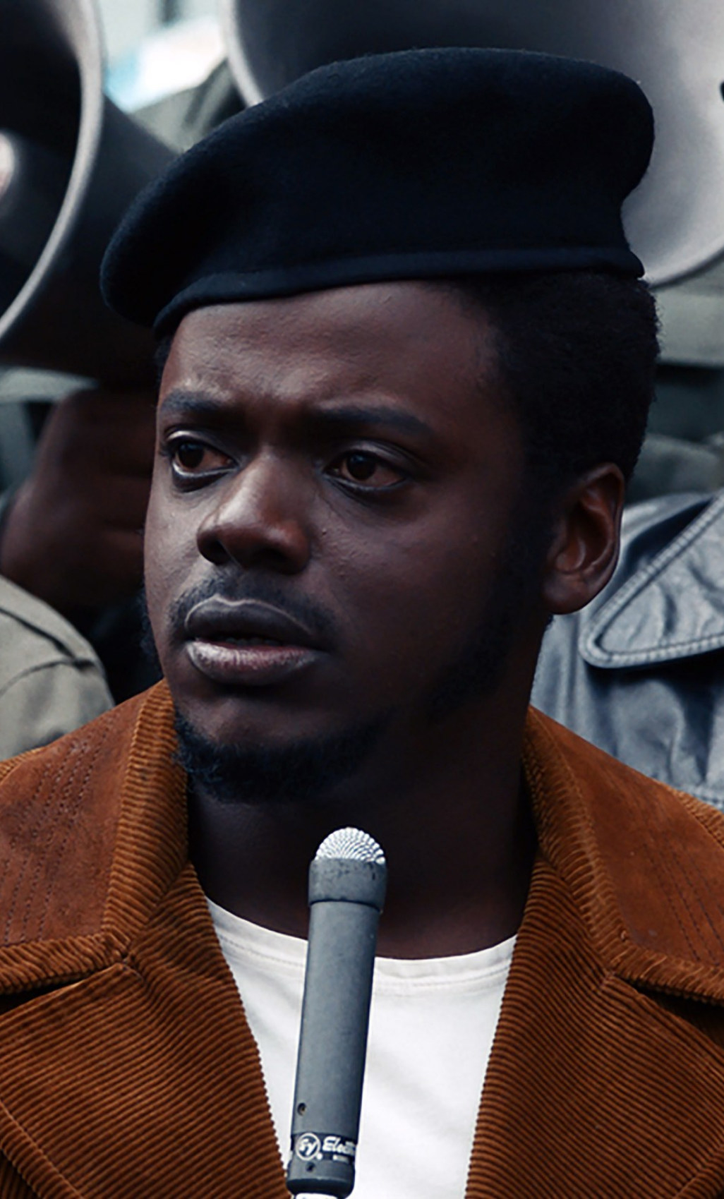 Kaluuya wearing a beret, corduroy jacket, and speaking into a microphone