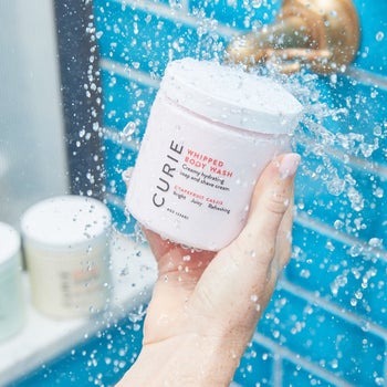 hand holding jar of the body wash in the shower