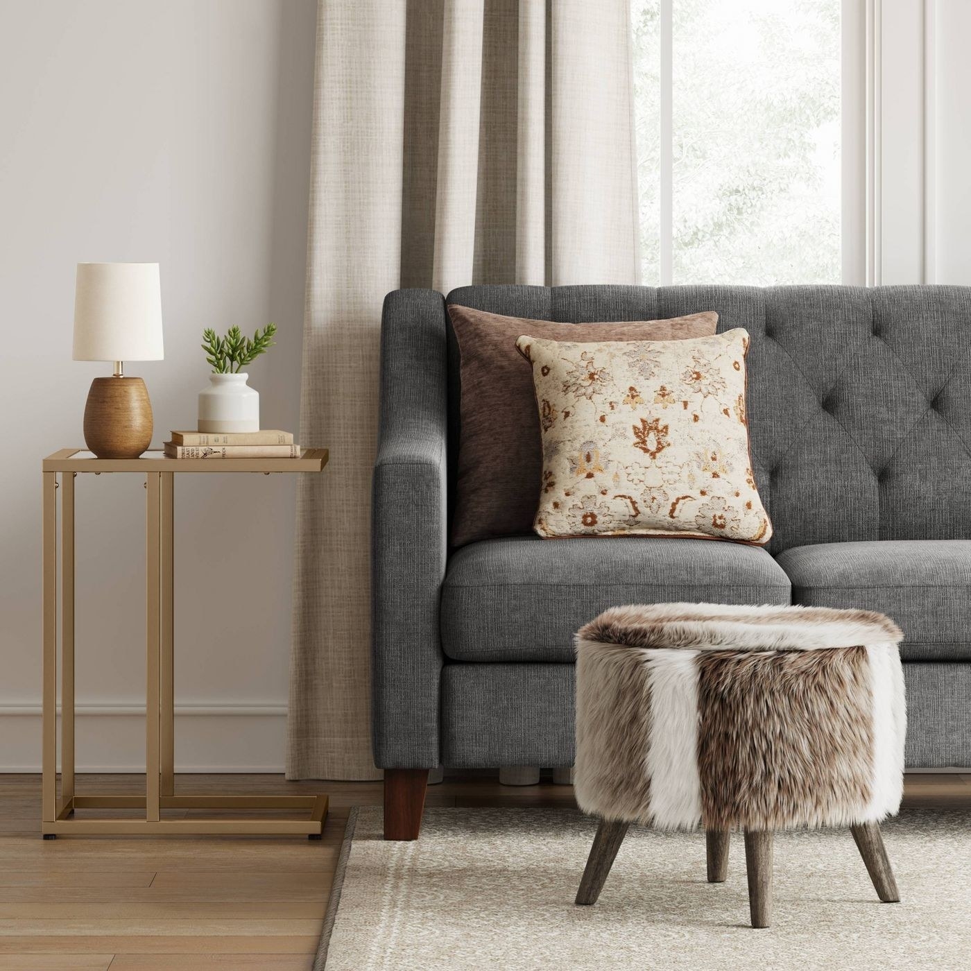 A brown and white faux fur ottoman in room with grey couch