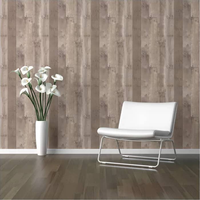 Brown wood wall behind white chair and vase with flowers