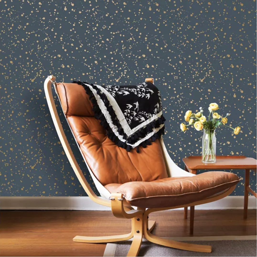 Brown leather chair in front of navy blue and gold metallic splattered wall