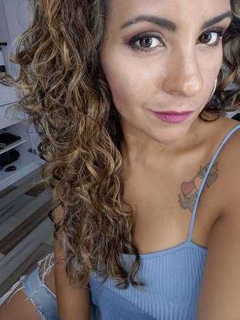 A customer shows off her soft and shiny curly hair after using the Moroccan Argan Oil Shampoo and Conditioner