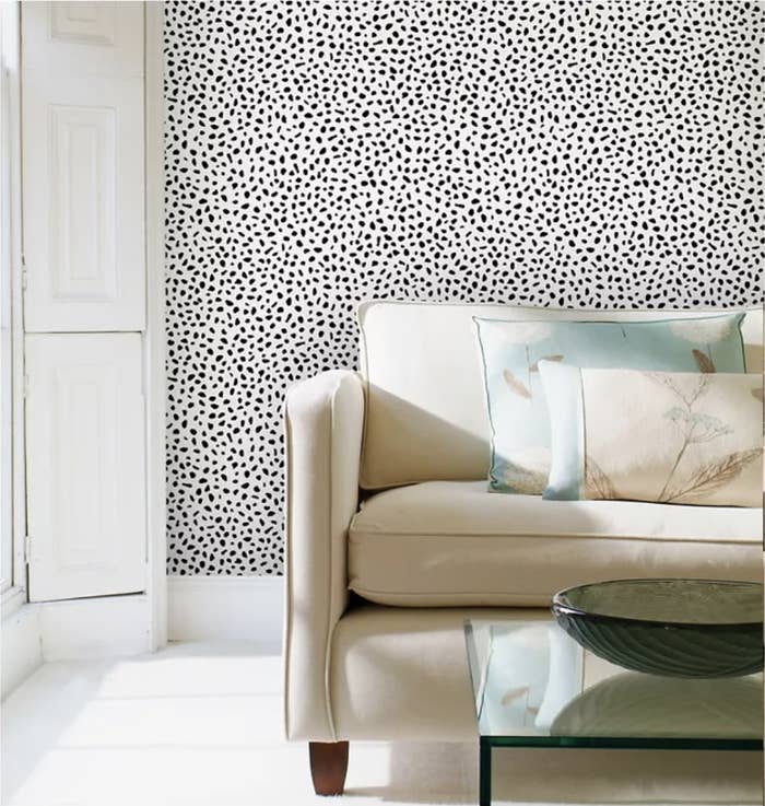 Cream couch in front of black and white speckled polka dot wall