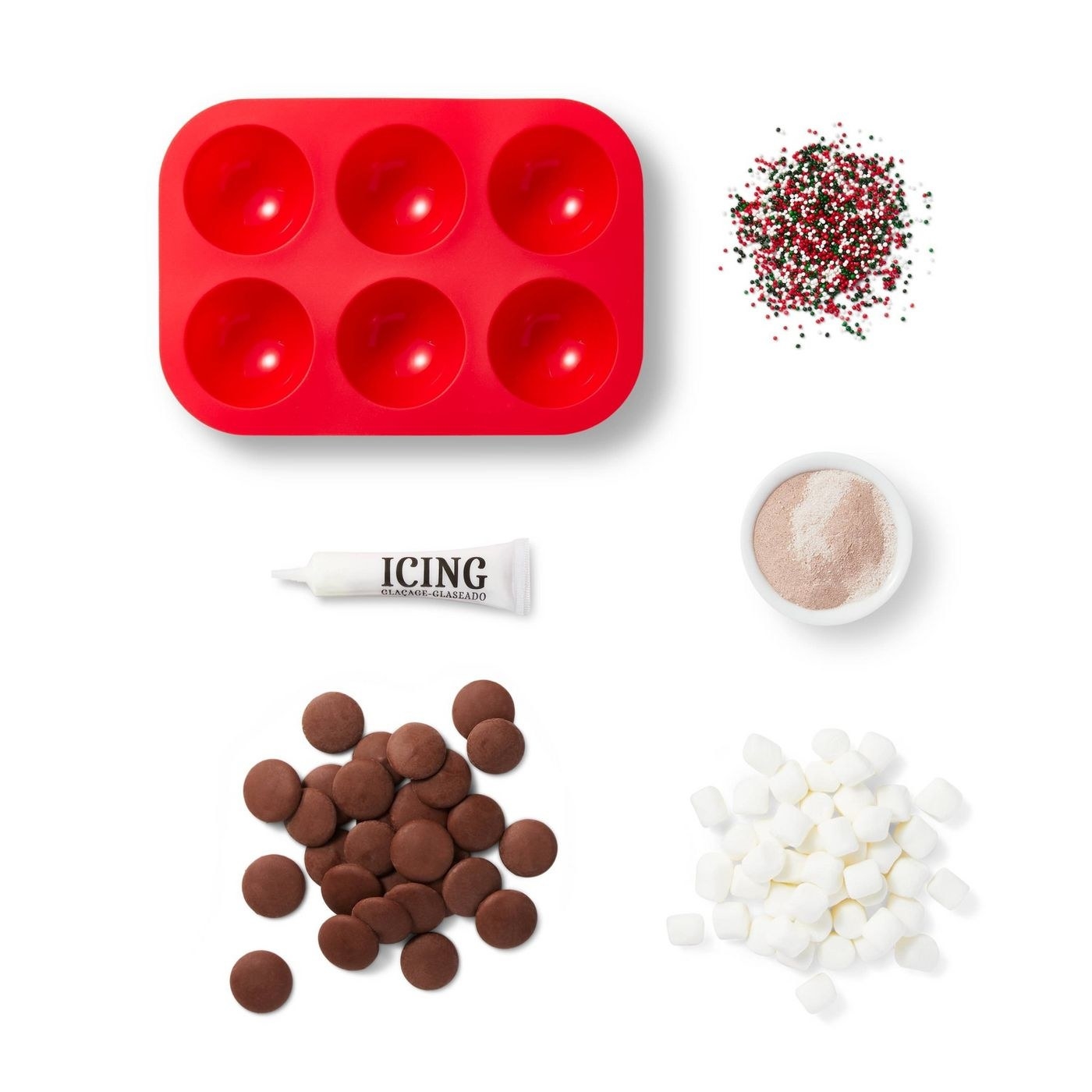 A hot chocolate bomb kit with chocolate, marshmallows, white tube of icing, sprinkles, red mold and hot chocolate mix