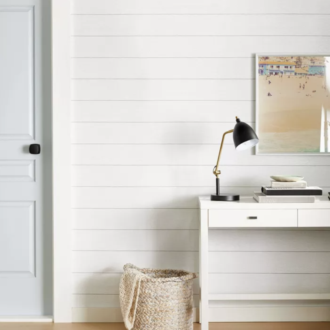 White desk and woven basket in front of white Shiplap wall