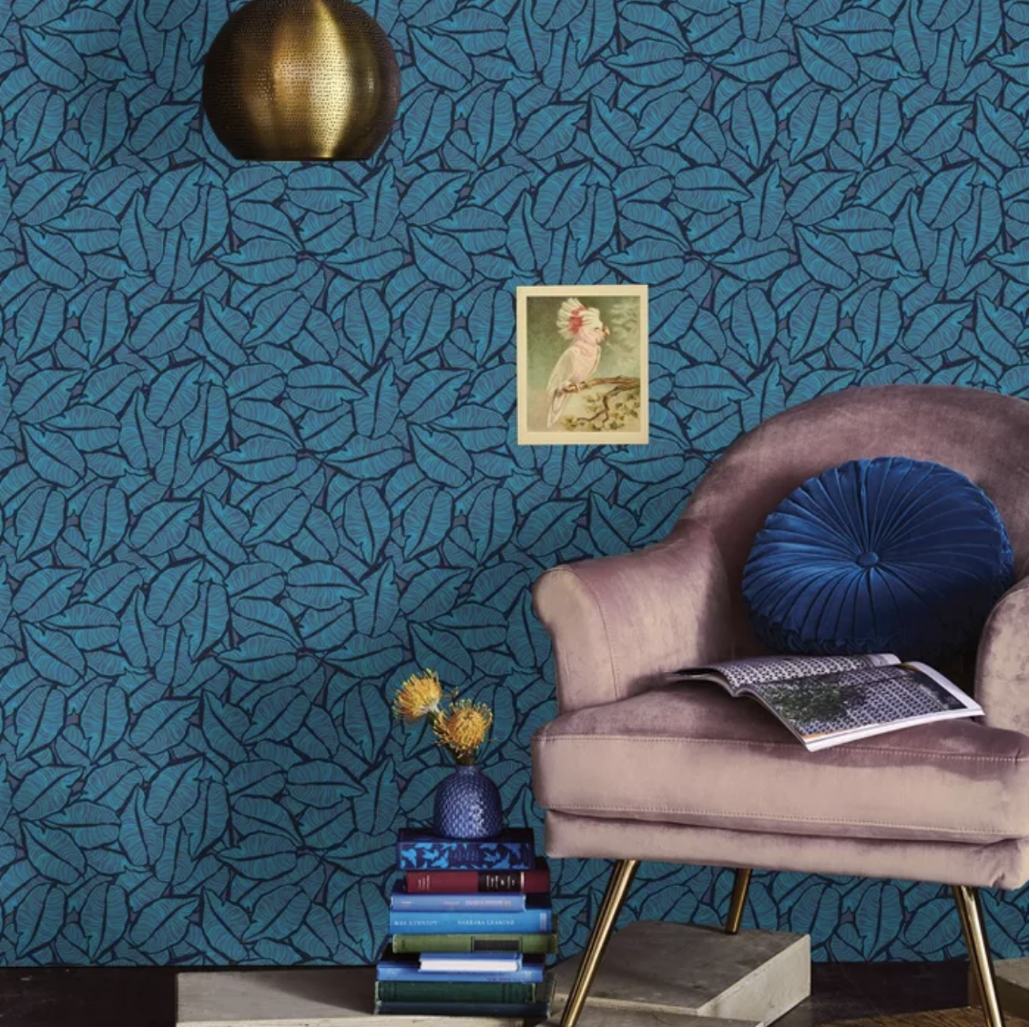 Blue leaf wallpaper behind purple velvet chairs and stack of books