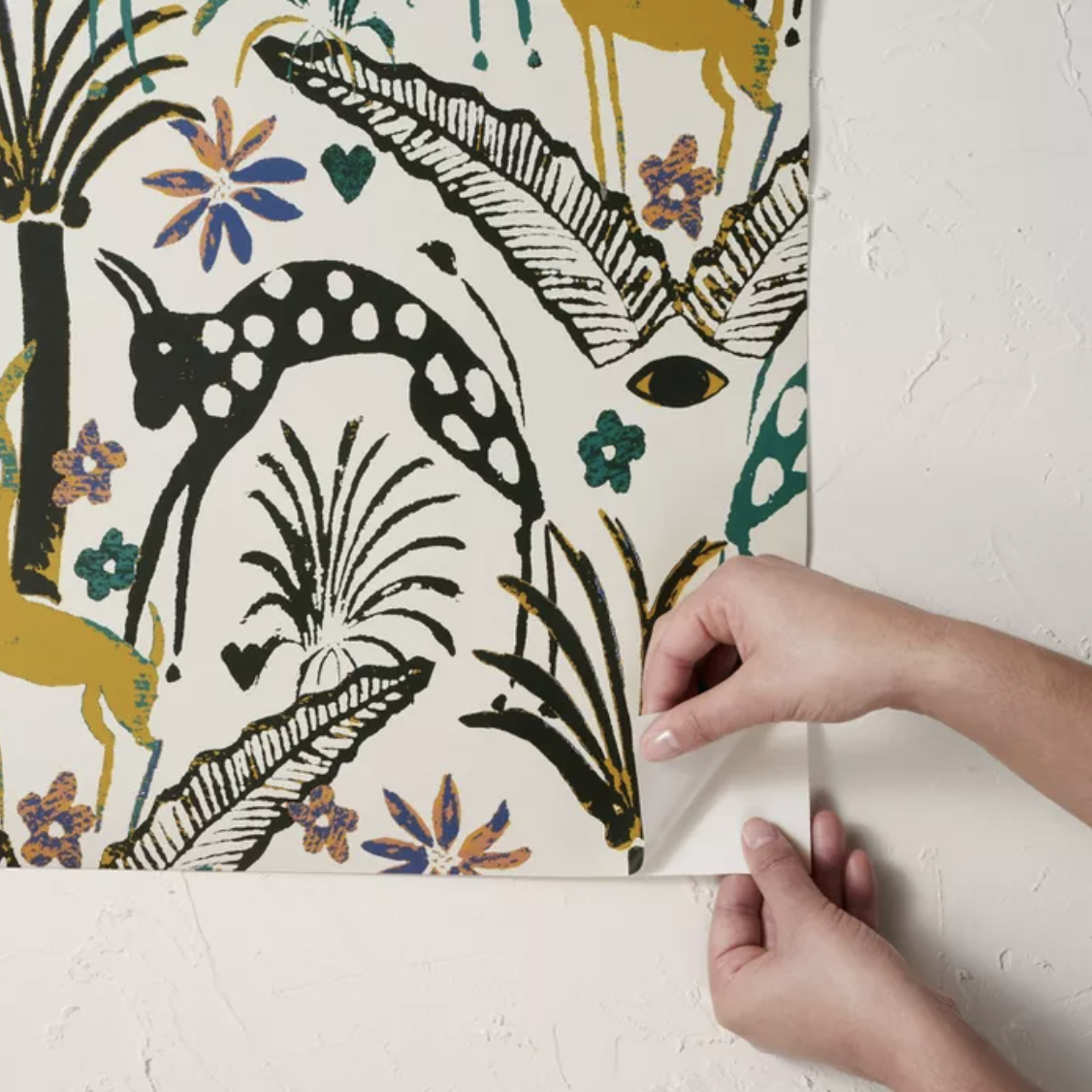 Model peeling back multicolored jungle-themed wallpaper