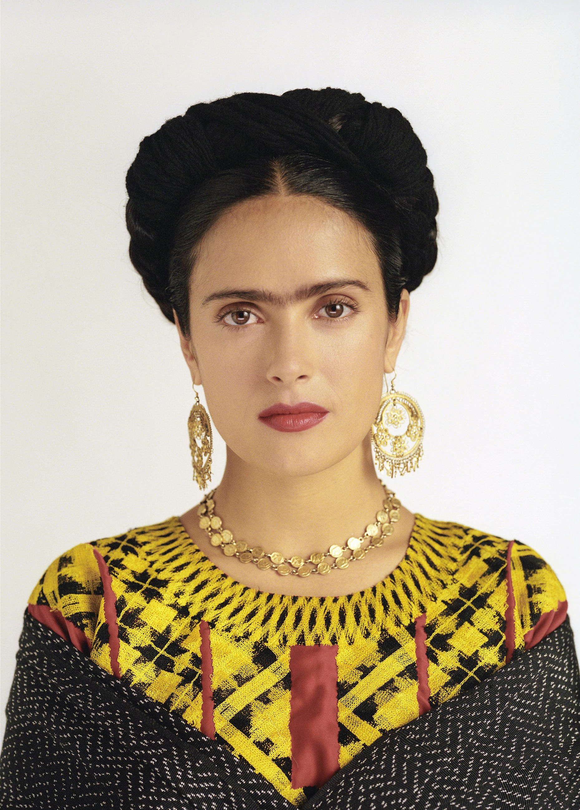 Hayek with a unibrow, wearing colorful gown, and gold jewelry in &quot;Frida&quot;