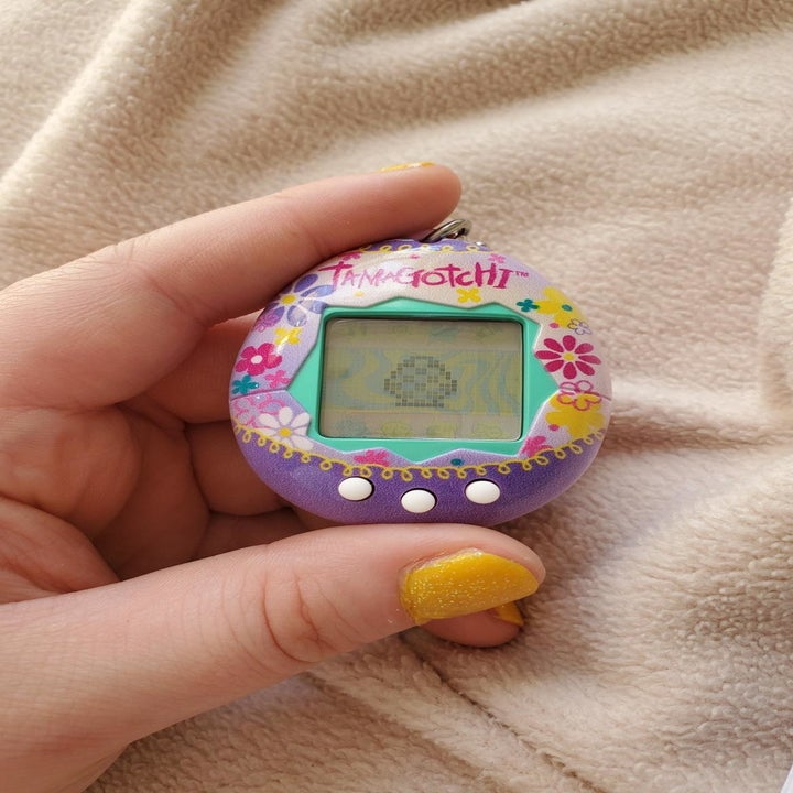 a reviewer holding their tamagotchi