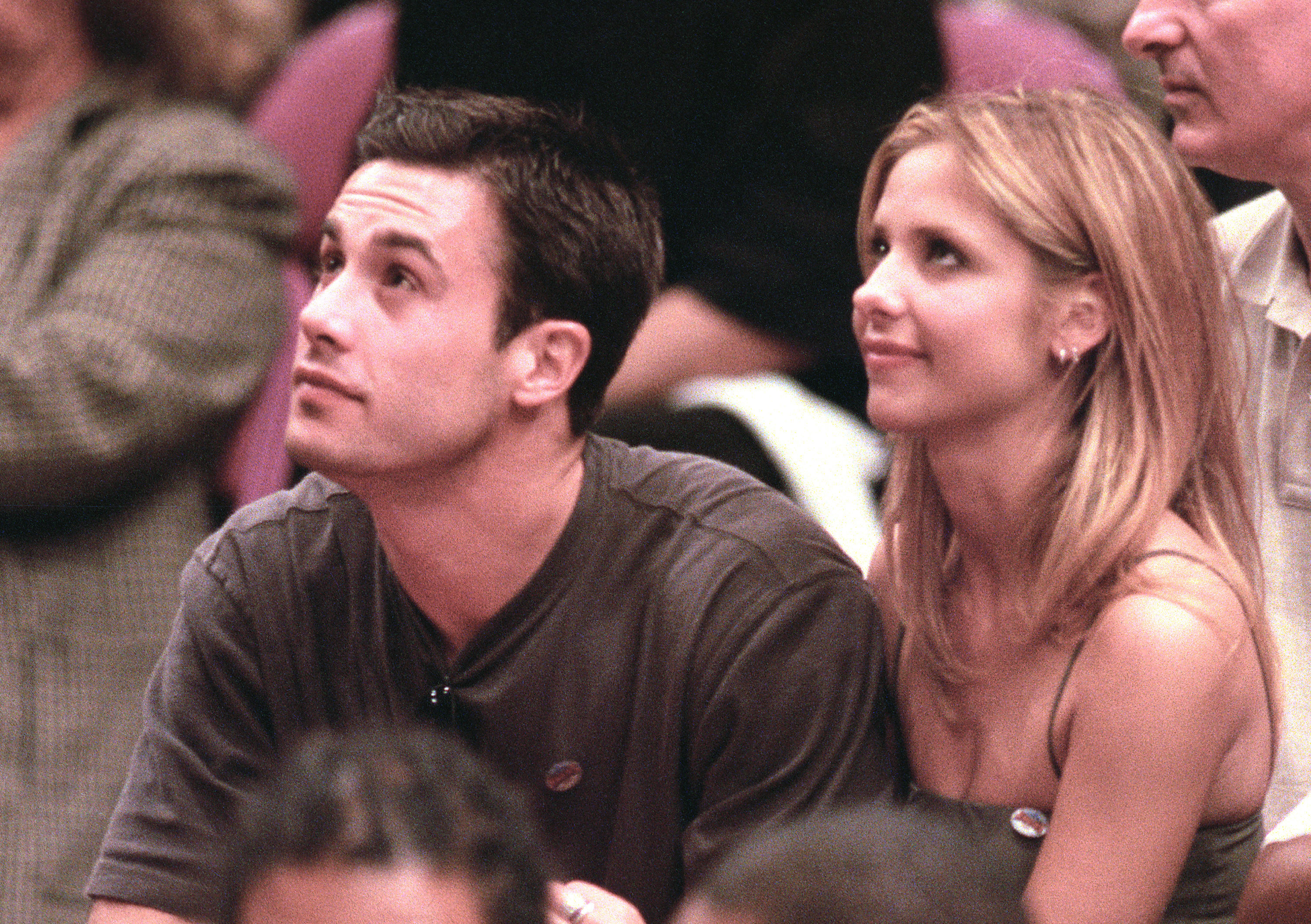 Gellar and Prinze look up at a basketball game