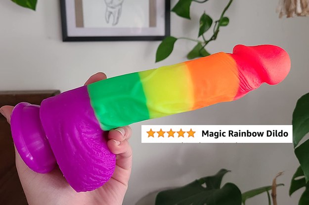 Reviewer holding rainbow stripe dildo with five star review