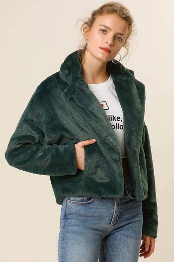A model wearing the cropped open jacket in dark green. It hits at the waist