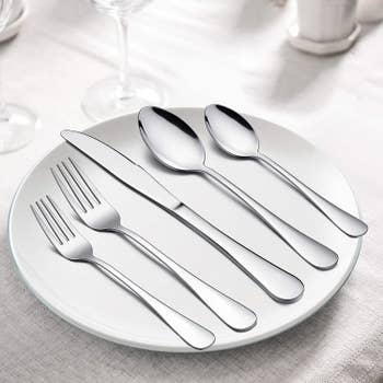 The forks, spoons, and butter knife on top of a dinner plate