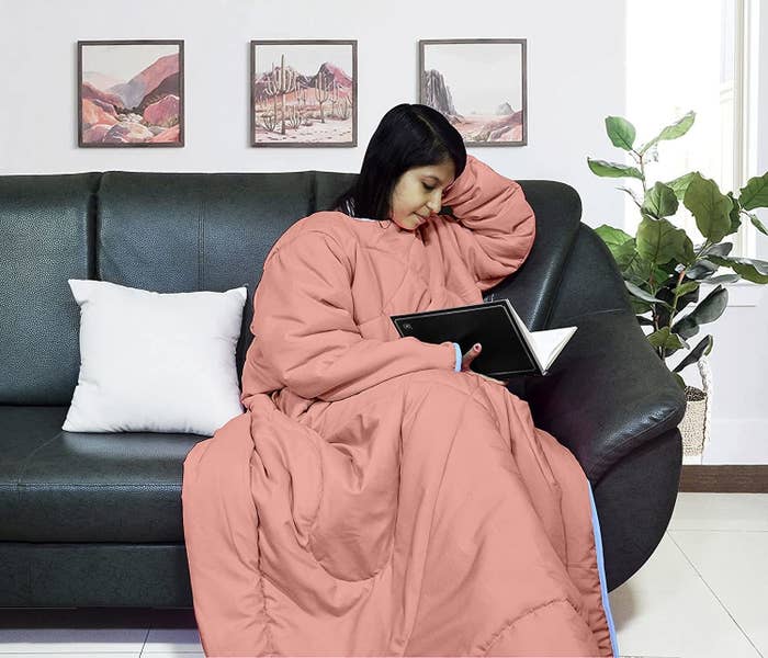 A woman in a wearable blanket reading a book