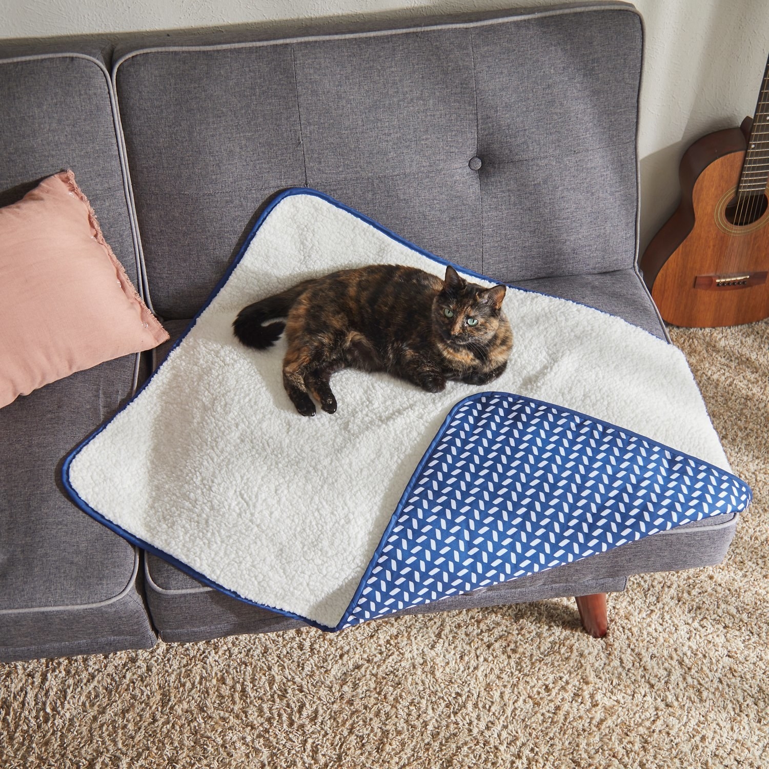 cat lying on a sherpa blanket with blue patterned side