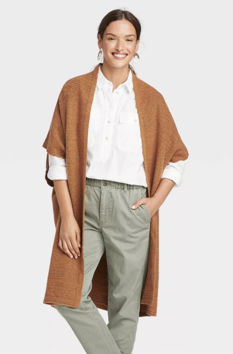 model wearing rust colored knit wrap with grey jeans