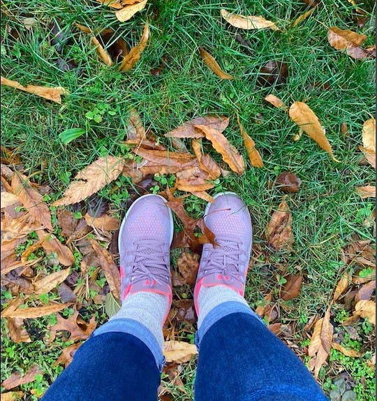 A person is standing on grass that is coated with different leaves.