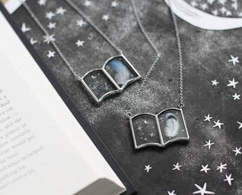 Two book necklaces with printed feathers and stars in them