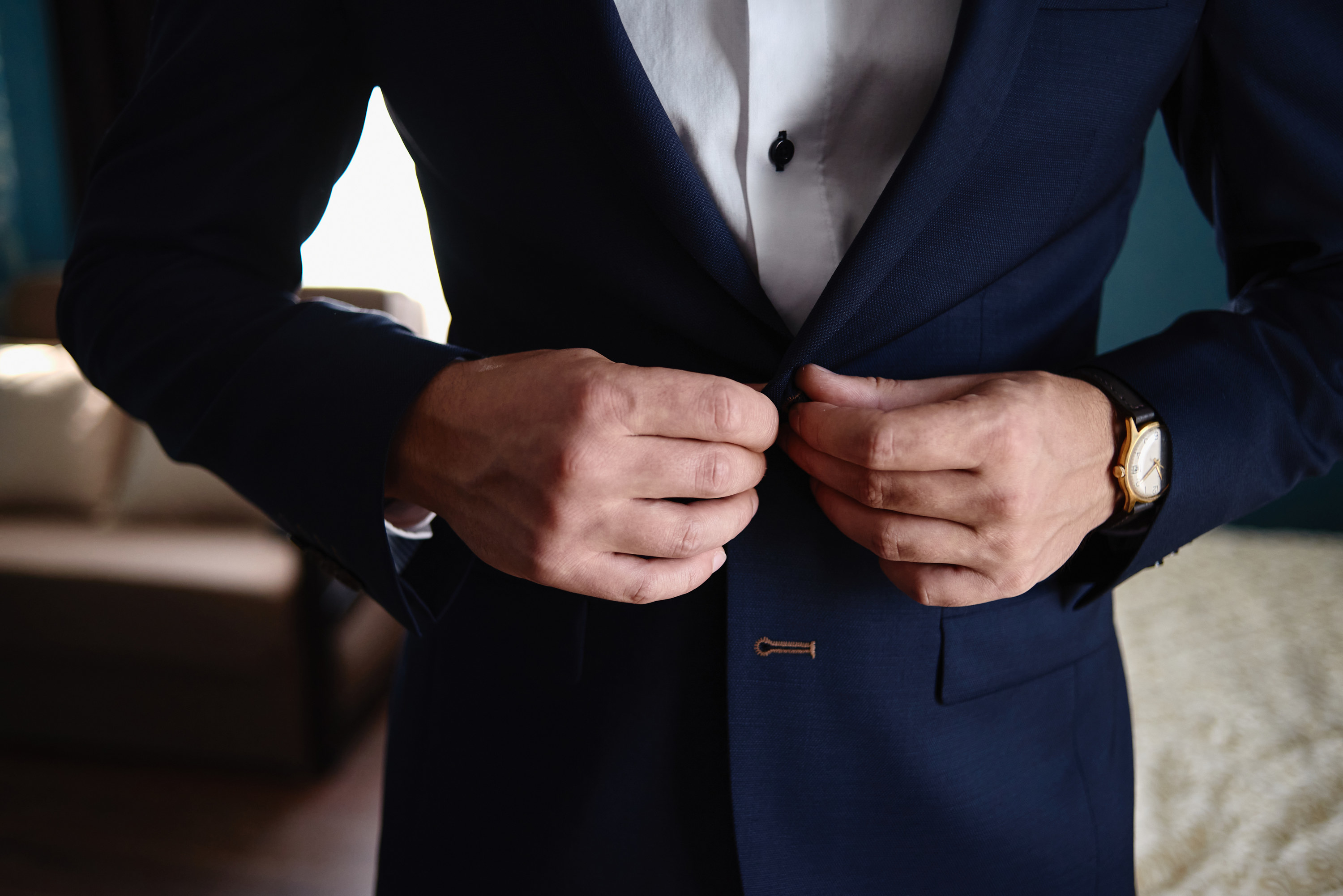 A man buttoning his dark suit jacket