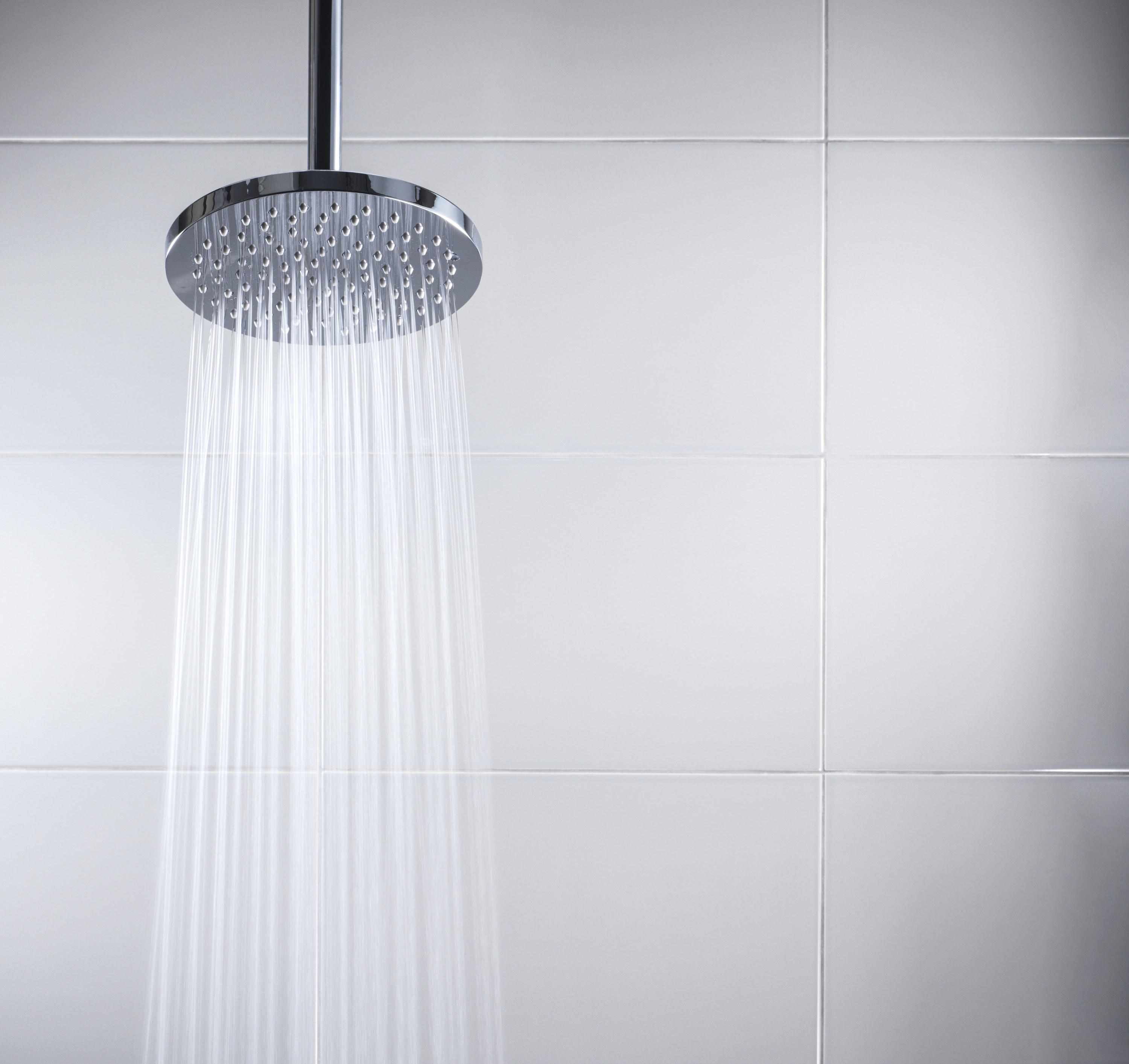 Water running from a shower head in a white tiled shower
