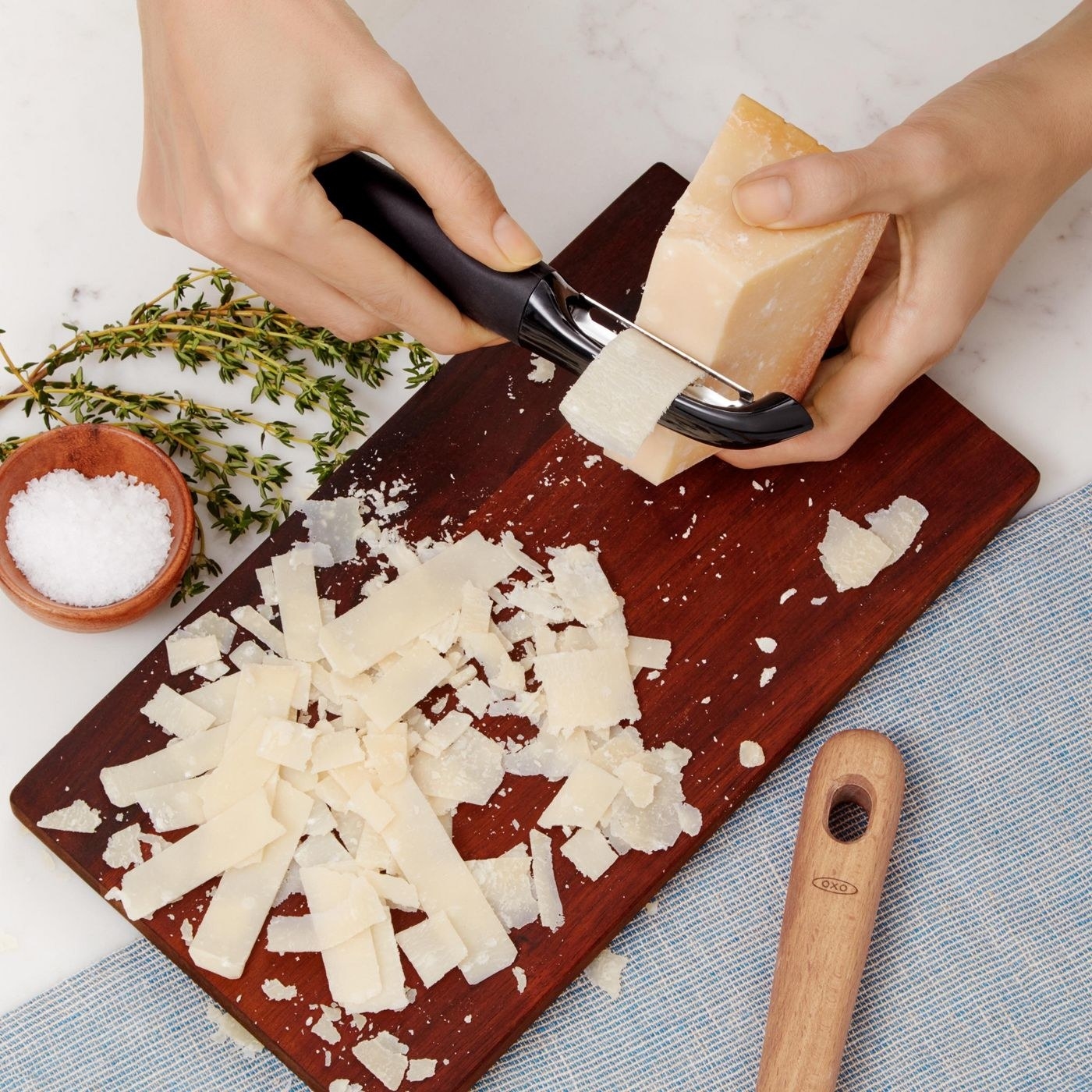 Model using peeler to slice off cheese