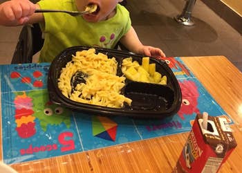 reviewer's child eating pasta on the disposable placemat stuck on a table