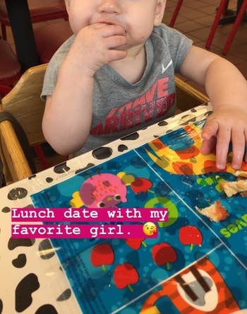 reviewer's photo of their child eating finger food on the disposable placemat stuck on a table at lunch
