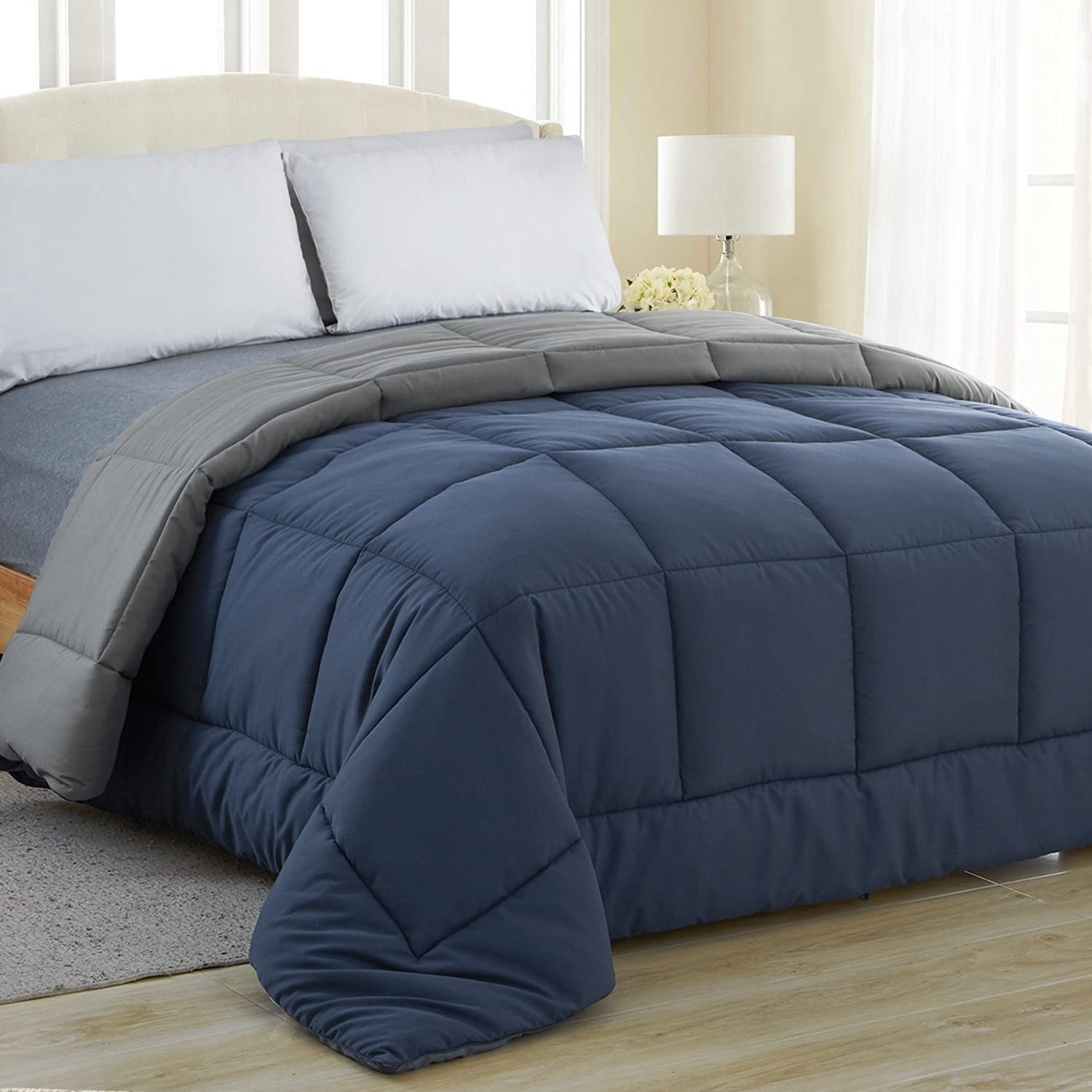 navy blue comforter and gray reversible comforter on mattress in bedroom