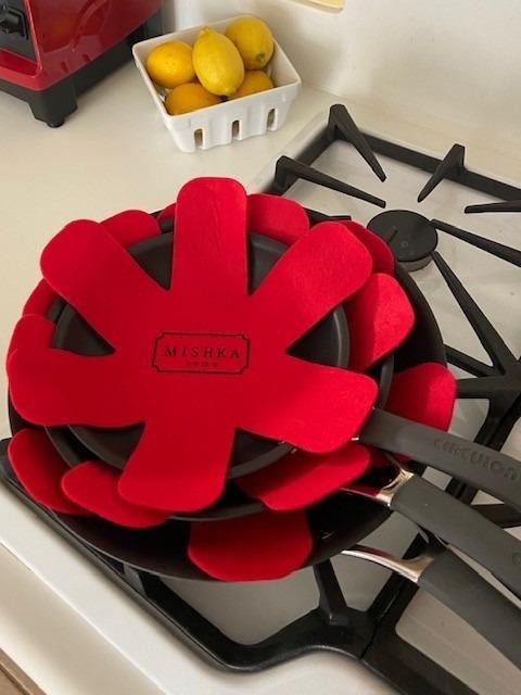 Reviewer image of three pans with red felt pan protectors on top of stove
