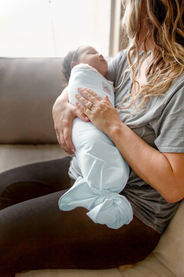 A model holding a baby in the sky blue swaddle